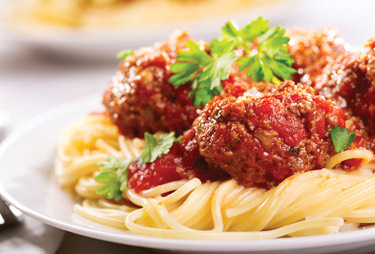 A close up of a plate of pasta with meat balls.