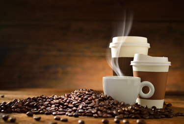 Three cups of coffee with coffee beans next to them.