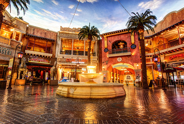 A fountain in the middle of restaurants and shops.