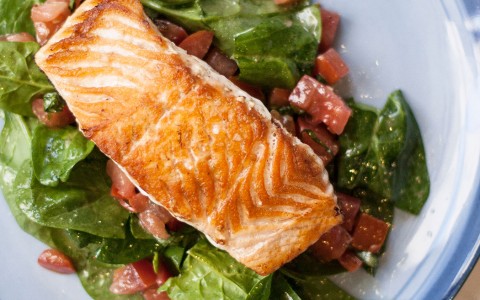 above photo of a salmon plate served with some salad and lime on the side