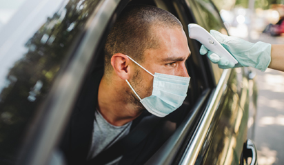 man in car with mask getting temperature check