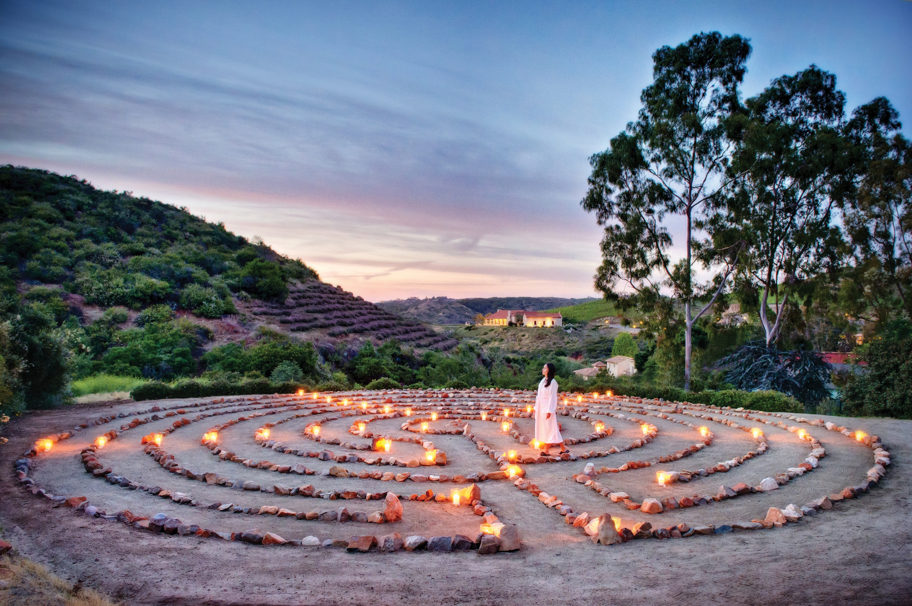 labyrinth meditation made of rocks with candles in a green valley