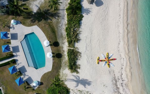 Aerial view of a pool next to the beach and some kayaks on the seashore