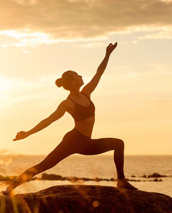 View of a woman doing a yoga pose at sunrise