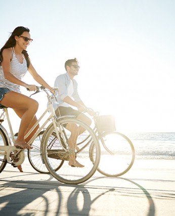A man and a woman riding a bike next to the sea