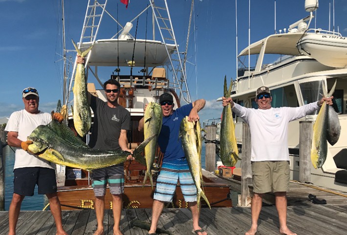 Three happy men showing their catch after fishing