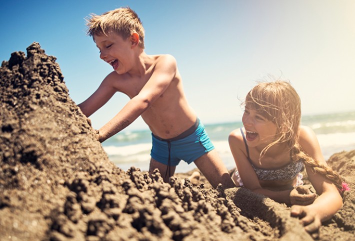 Two happy kids doing a sea sand castle