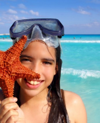 A girl wearing a snorkel mask, holding starfish