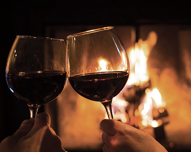 two glasses of wine in front of a fire