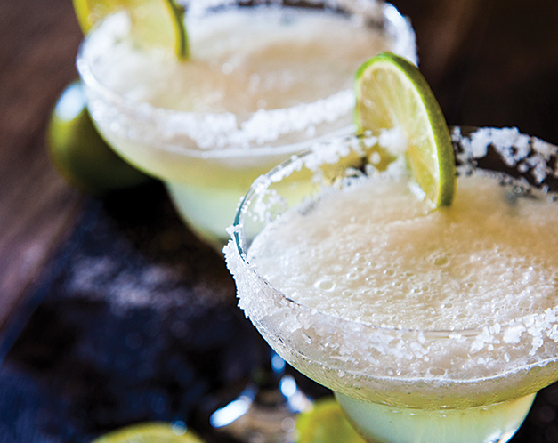 two margarita glasses with salt rims and a lime garnish