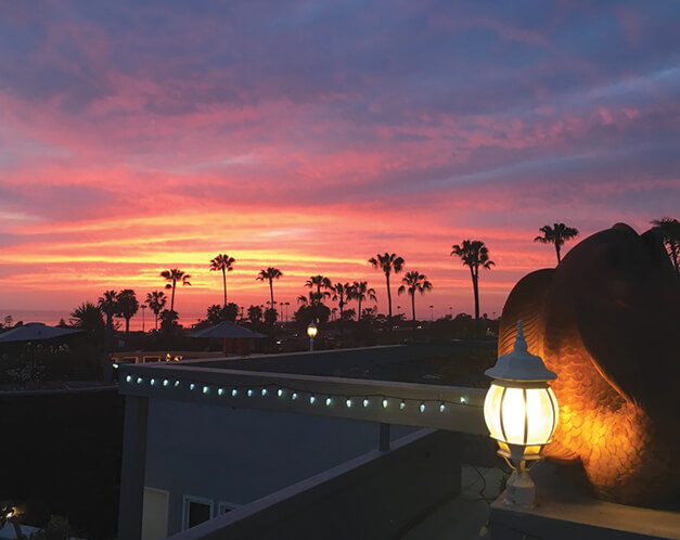 a pink, purple, and orange sunset seen from a rooftop with string lights
