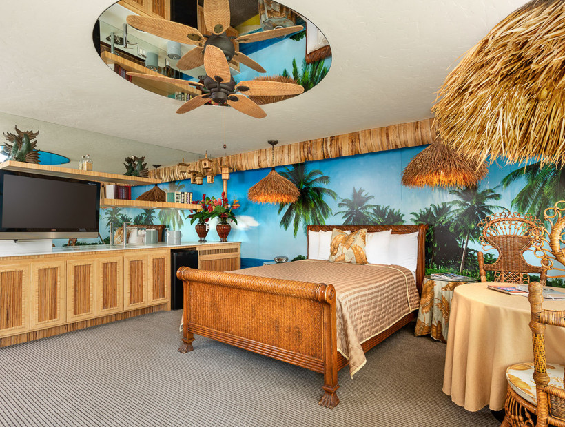 guest room with bamboo inspired furniture, palm tree mural on the wall, bed, dresser, and table