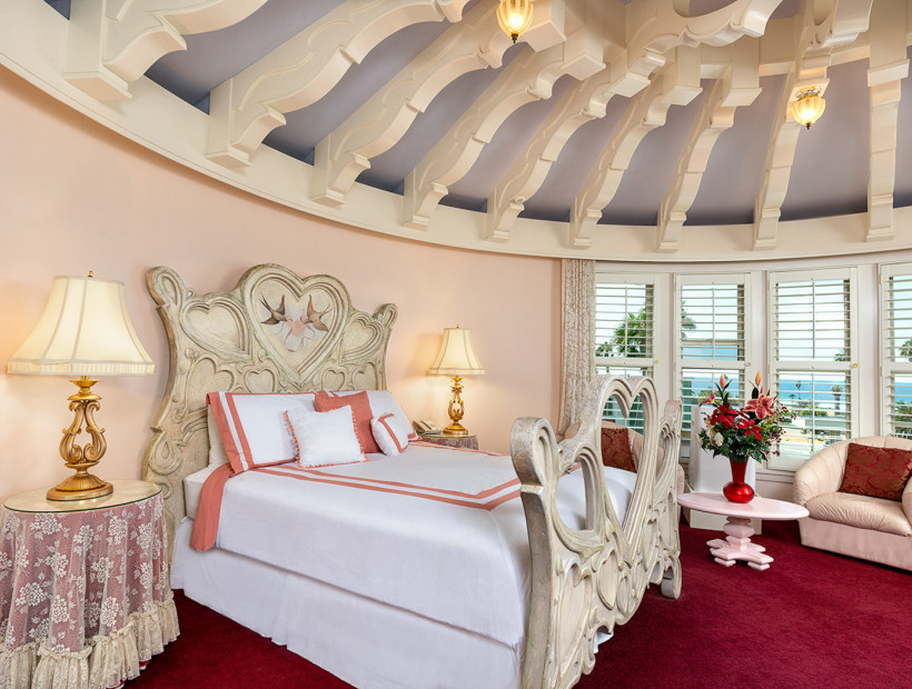 guest room with ornate moldings on the rounded ceiling, white linens, red carpet, and lounging chairs