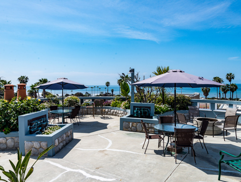 patio area with table seating, umbrellas, and a view of the ocean