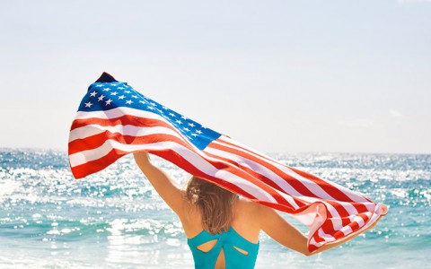Woman at the beach holding the American flag behind her head