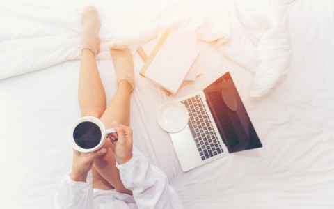 in bed with coffee and laptop
