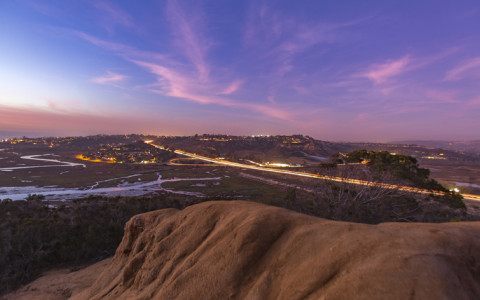 a view of open land and a highway with a stream of lights