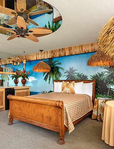 guest room with bamboo inspired furniture, palm tree mural on the wall, bed, dresser, and table