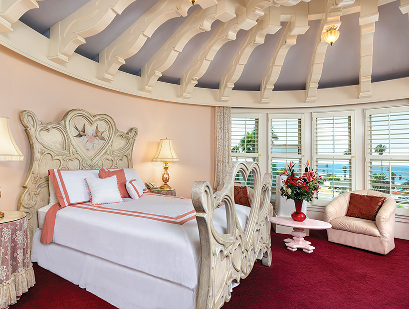 guest room with ornate moldings on the rounded ceiling, white linens, red carpet, and lounging chairs