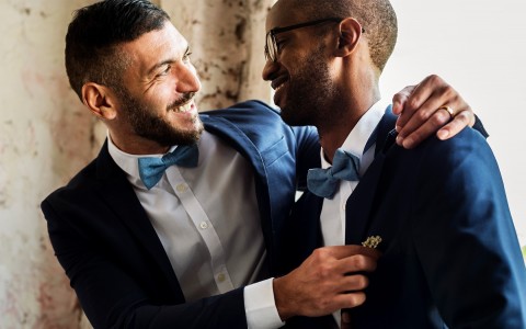 grooms smiling while wearing suits and navy blue bowties 