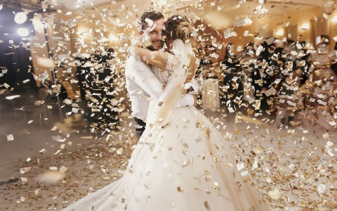 bride and groom dancing while being surrounded by gold confetti