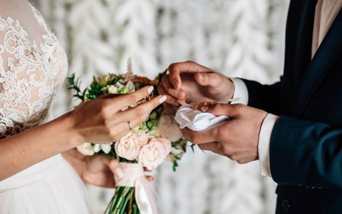 close up of bride and groom holding rings