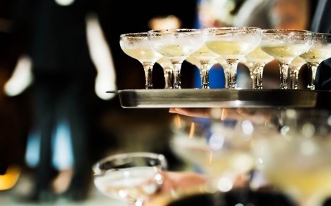 server holding champagne glasses on tray