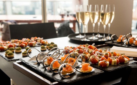 small trays of food with champagne glasses behind it 
