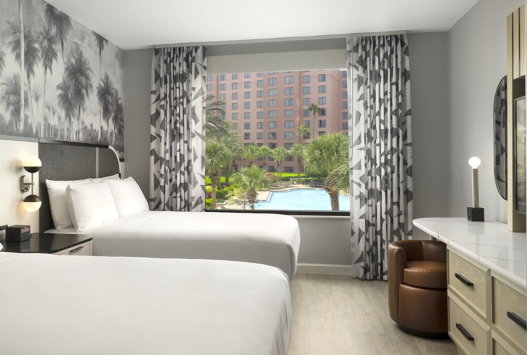 two beds with a black and white canvas behind the bed and black and white curtains with a view of the pool