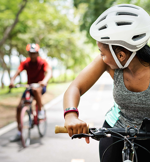 woman riding a bike while wearing a white helmet and looking back at the person behind her