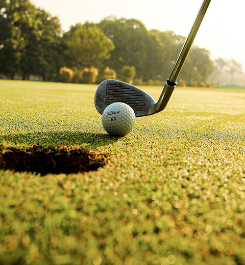 close up of a golf club and gold ball