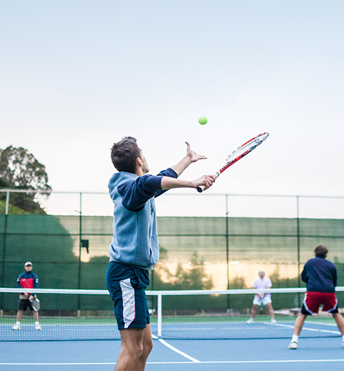 man throwing a tennis ball up in the air