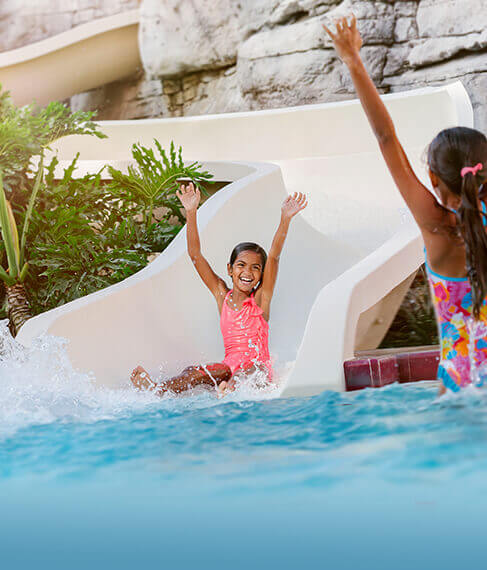 two girls having fun on the slide and in the pool