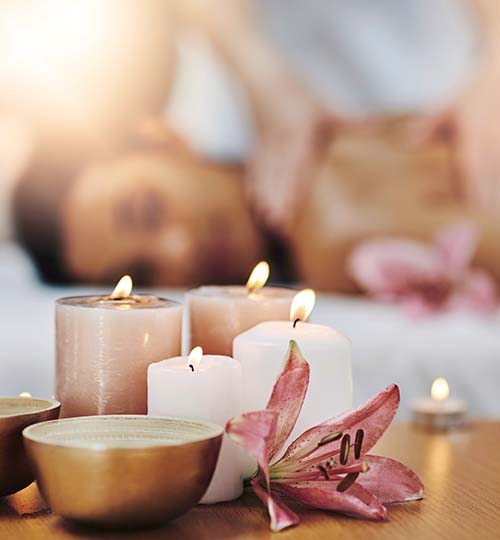 woman getting a massage while the candles and flower are in focus
