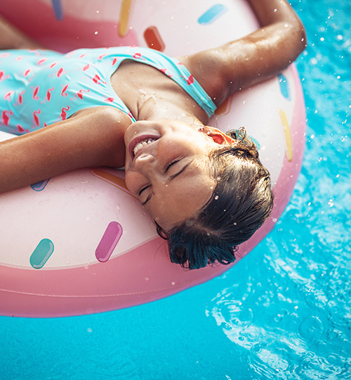 a little girl laying in a donut float in a pool