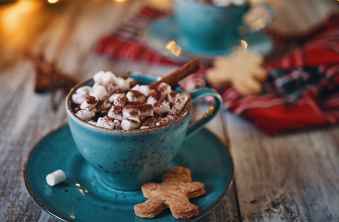 hot cocoa in a blue mug with a gingerbread man cookie