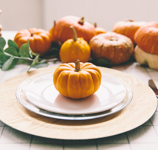 thanksgiving place setting with pumpkins in the background