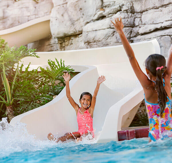 two girls having fun in a pool with a slide
