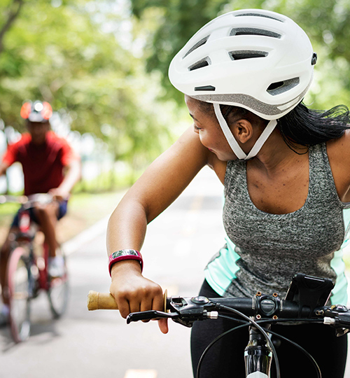 woman riding a bike with a white helmet while looking behind her at the other biker