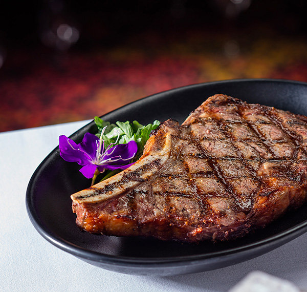 close up image of a steak on a black plate and decorative flower