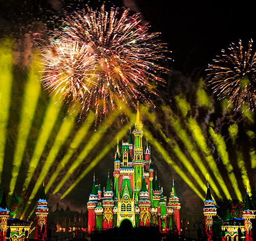 view of magic kingdom Disney castle at night with projected colored lights