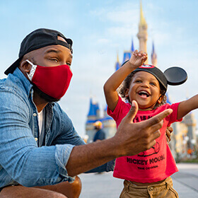 Dad wearing mask and his son enjoying a beautiful day at Magic Kingdom