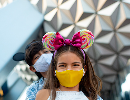 Happy young girl with a mask and colorful mickey mouse ears at Disney