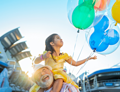 a little girl on her grandpas shoulder holding balloons