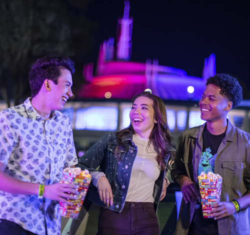 three guests at Disney After Hours chatting and enjoying popcorn