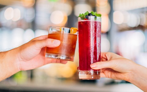 two hands holding cocktails