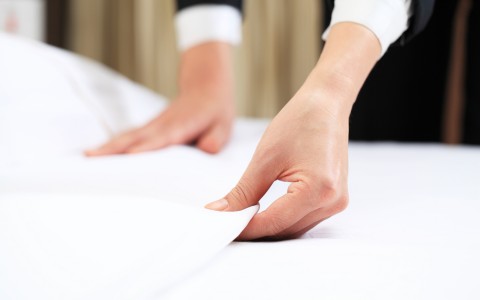 hands fixing bed sheets