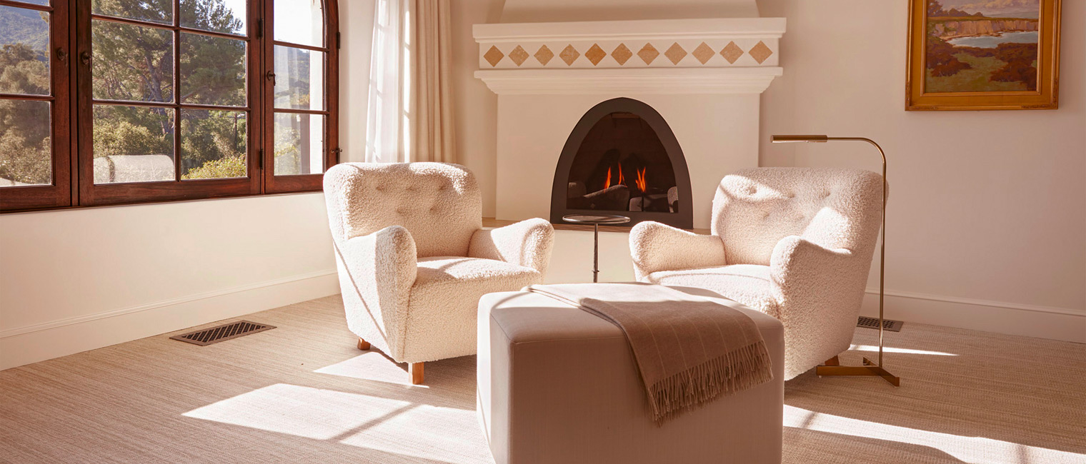 Two fluffy white chairs in front of a fire place