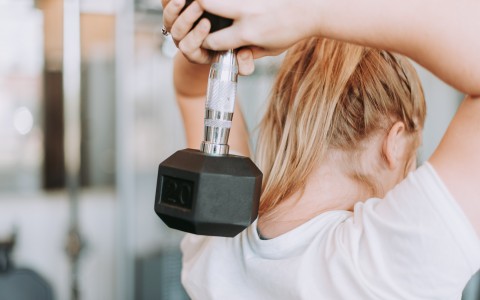 woman holding a dumbbell  weight behind her head