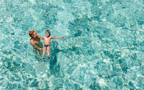 Aerial view of a mother and her kid swimming on a pool